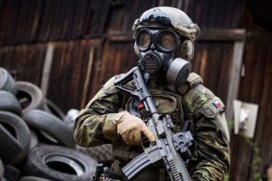 A military on the field wearing a gas mask.