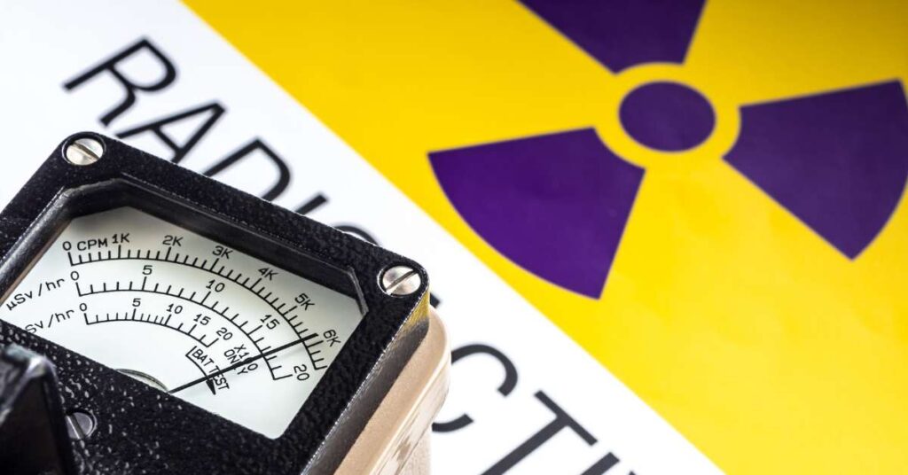 A geiger counter on top of a warning sign that reads "RADIOACTIVE."