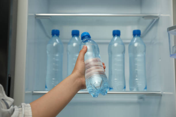 A hand holding a fresh tap water bottle for storage in the freezer. 