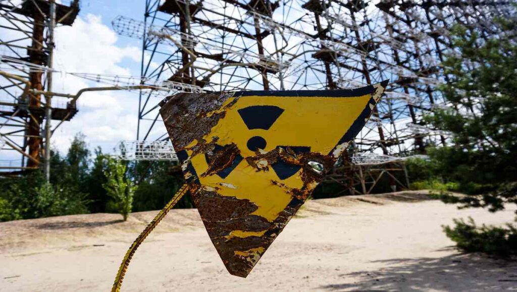 A rusted nuclear sign mounted on a metal post. 