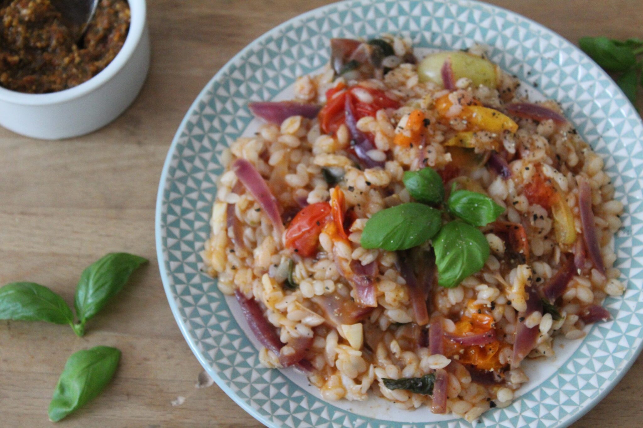 A bowl of rice and beans mixed with onion, tomato, garlic, and a herb on top. 