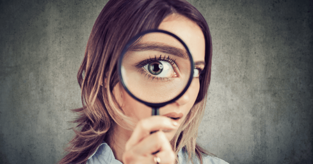 a woman holding a magnifying glass to inspect something